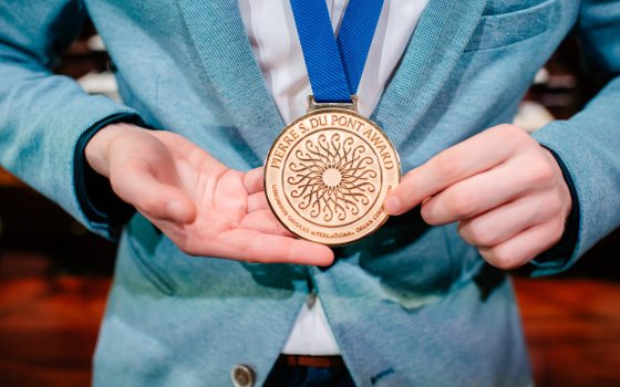 a person wearing a gold award who is holding it in their hands